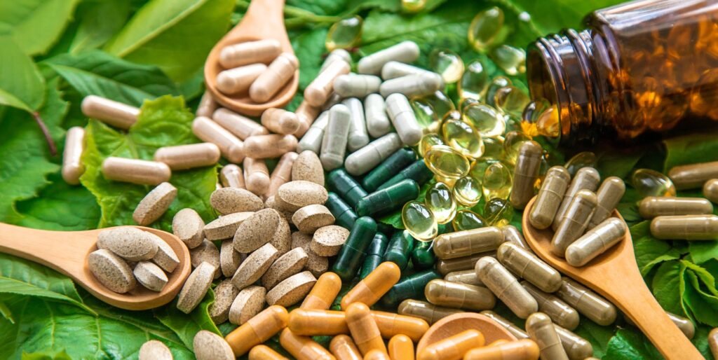 Capsules herb supplements on green leaves background. Selective focus.